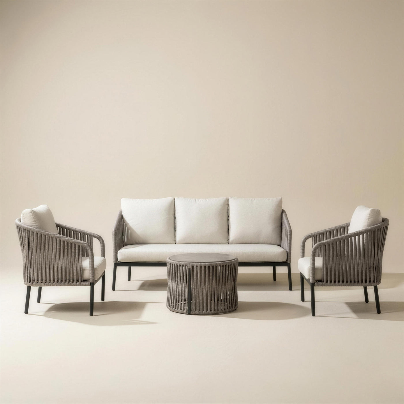 Conjunto de jardin Yina de 3 plazas: sofa, dos sillones y mesa de centro redonda con respaldos de cuerda trenzada gris y cojines crudo, sobre fondo neutro