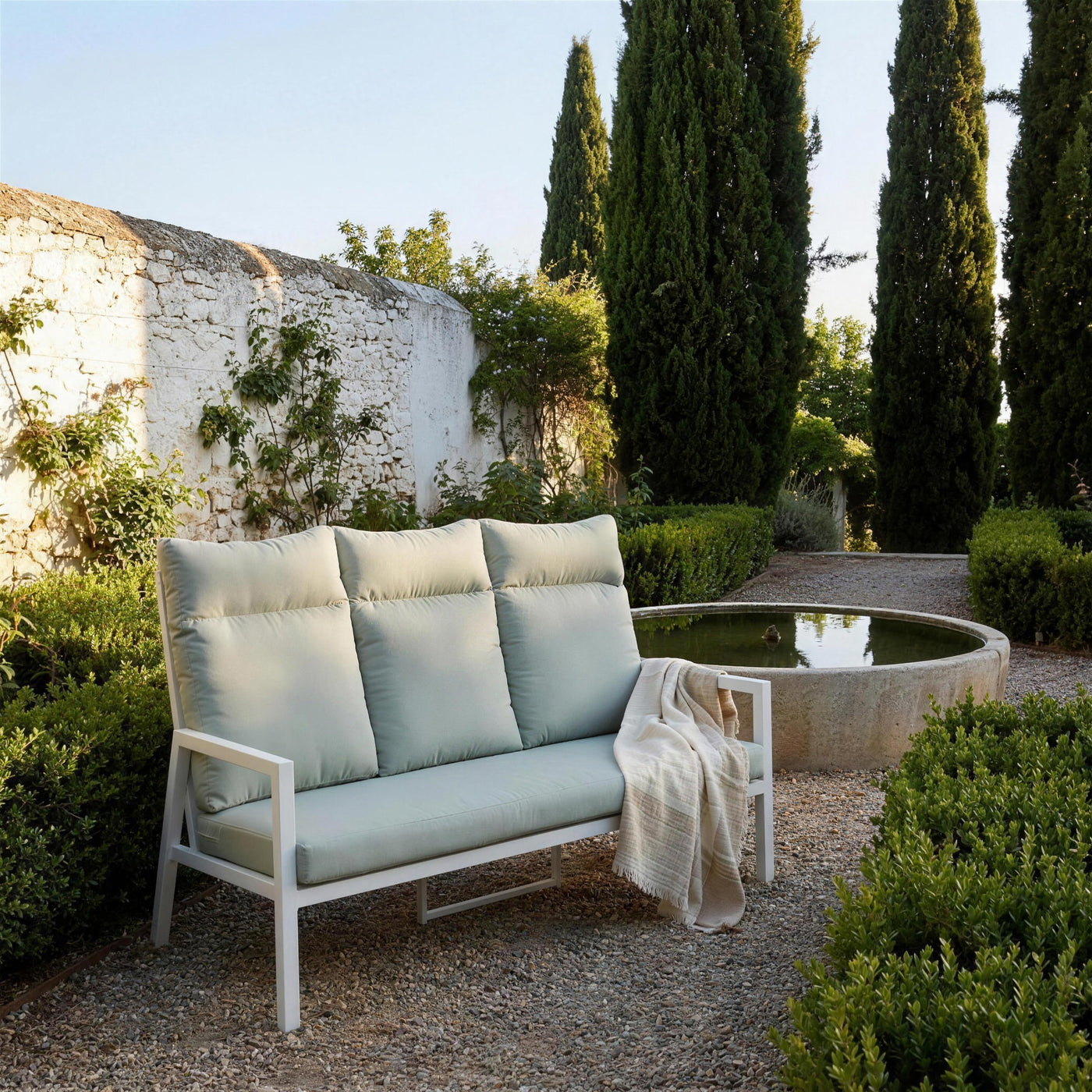 Sofa Haston de respaldo alto en el jardin de un carmen del Albaicin granadino, junto a una alberca de piedra, con cipreses y setos de mirto