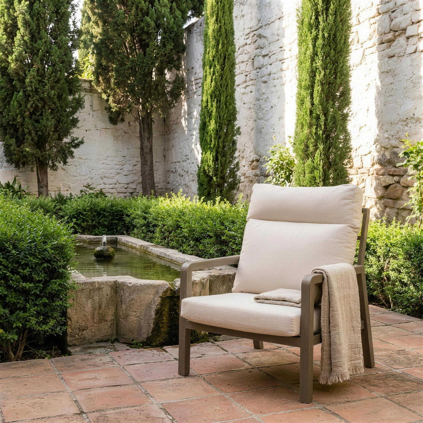Sillon Haston de respaldo alto en el jardin de un carmen del Albaicin granadino, junto a una alberca de piedra, con cipreses y setos de mirto