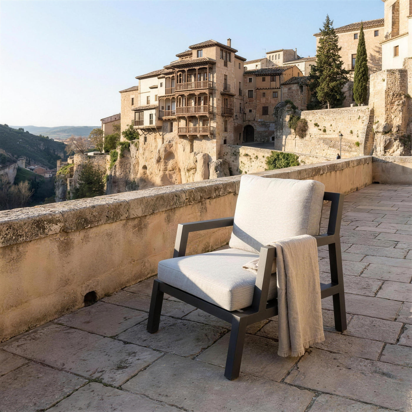 Sillon Leisa antracita en una terraza de piedra sobre el casco viejo de Cuenca, con las casas colgadas y la hoz del Huecar al fondo