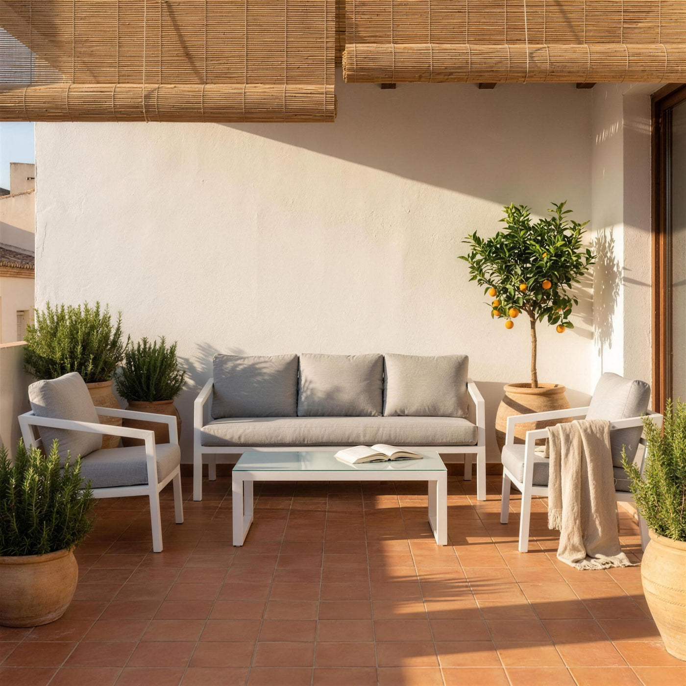 Conjunto Acapulco blanco en una terraza valenciana de suelo de barro, con persianas de esparto, romero y un naranjo en tinaja