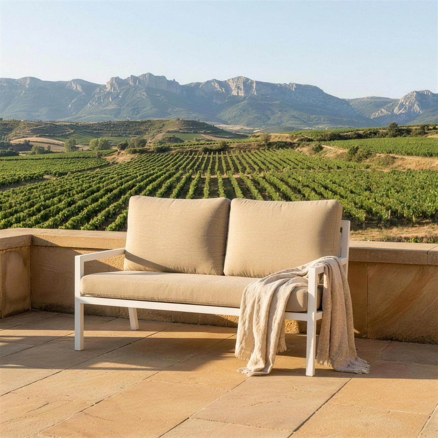 Sofa Dounvil de 2 plazas en una terraza de piedra arenisca sobre los vinedos de La Rioja, con la Sierra de Cantabria al fondo