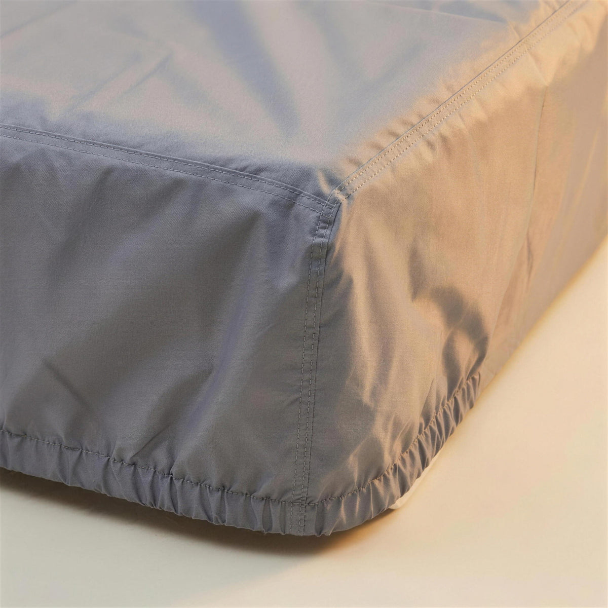 Detalle de la costura reforzada y el dobladillo elastico de la funda protectora gris para tumbona de exterior