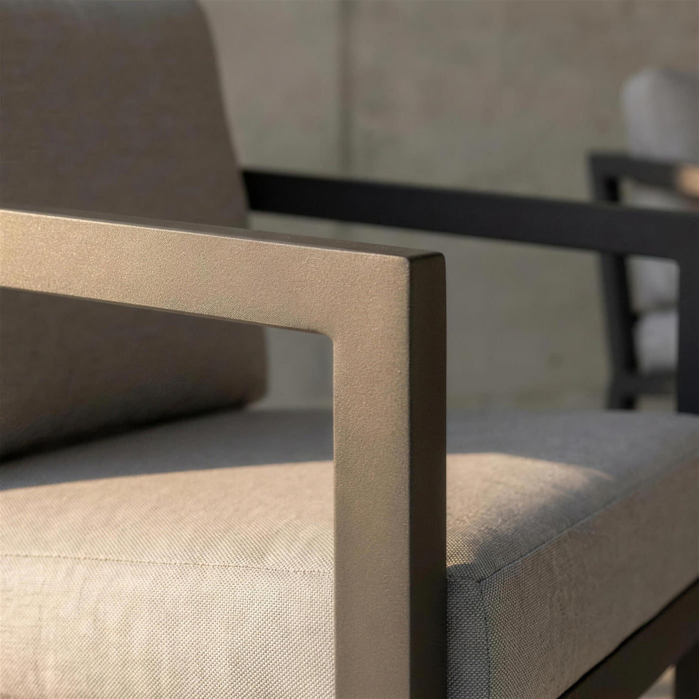 Detalle del perfil de aluminio antracita mate del sofa Acapulco y el canto del cojin gris claro con la luz rasante de la tarde