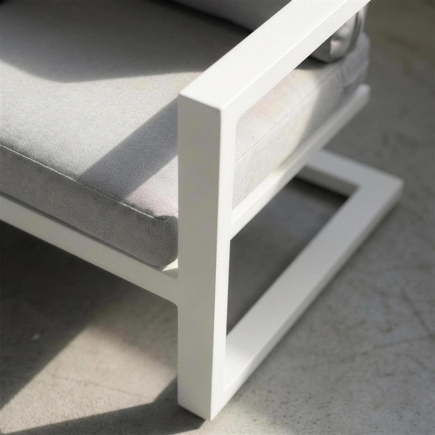 Detalle del brazo plano de aluminio blanco del sofa Manhatan y del quiebro de su base voladiza