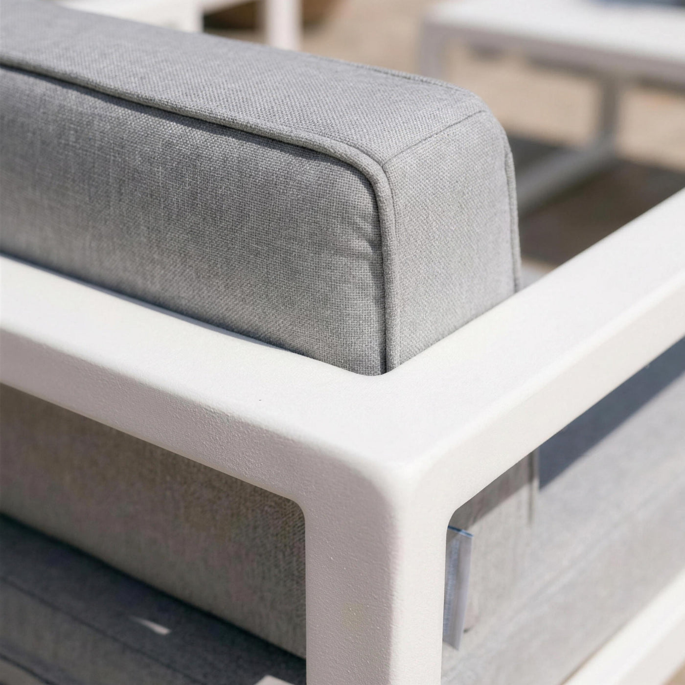 Detalle de la esquina redondeada del brazo de aluminio blanco del sillon Odin y del canto del cojin gris
