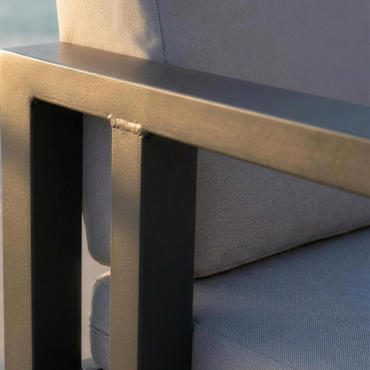 Detalle del brazo plano de aluminio antracita del sofa Odin y su cordon de soldadura, junto a la trama del cojin gris