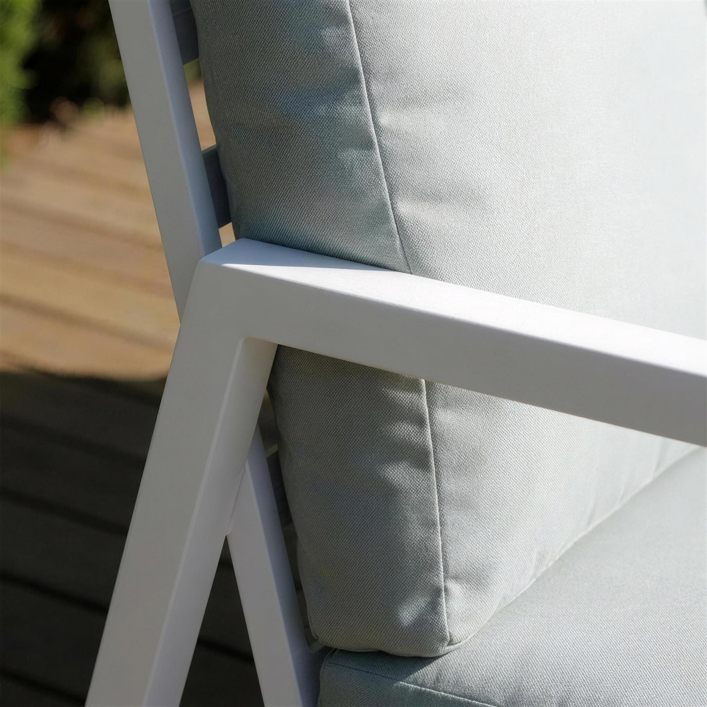 Detalle del brazo de aluminio blanco del sofa Haston en su union con la pata inclinada, junto al cojin verde salvia