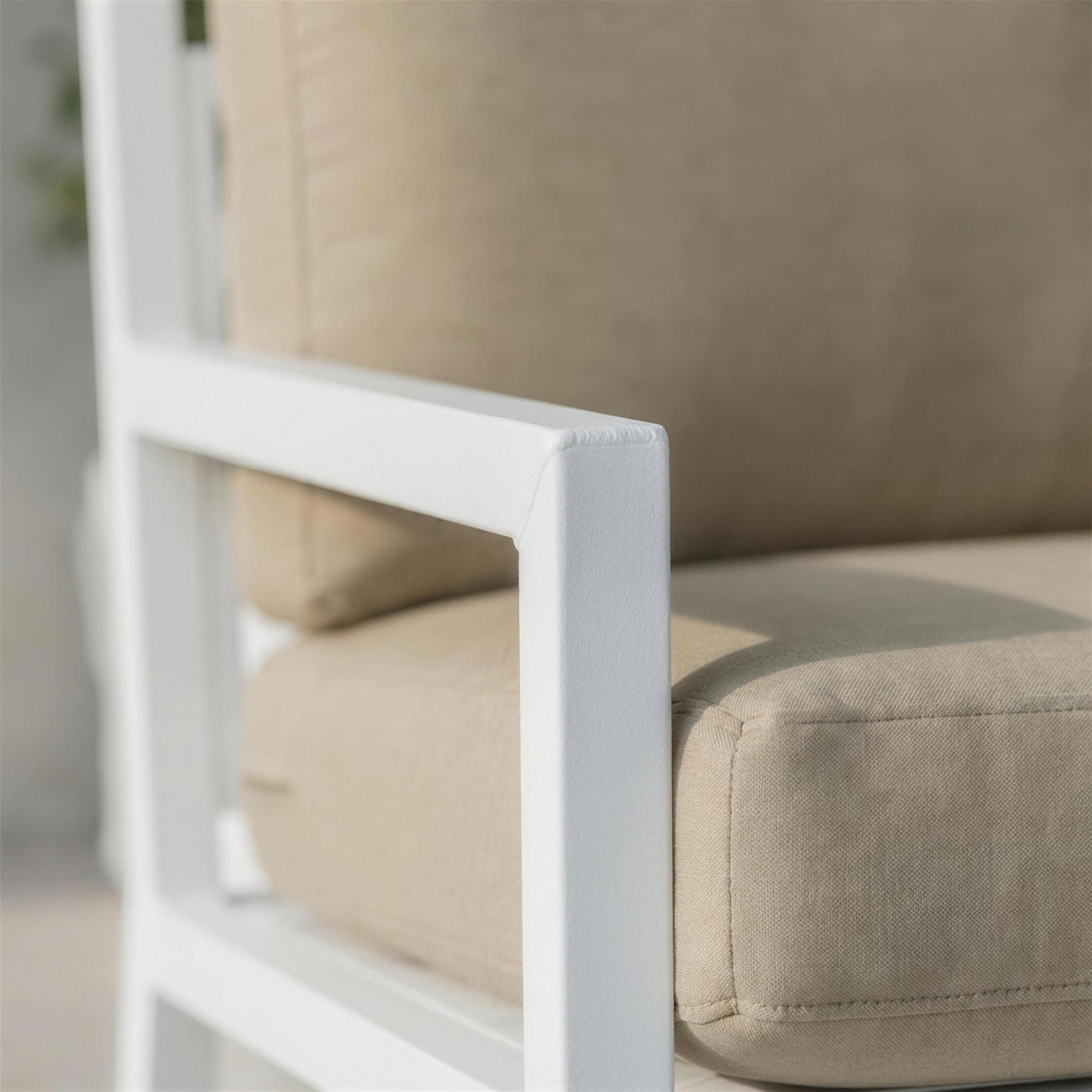 Detalle del brazo de aluminio blanco del sofa Dounvil en su union con la pata, junto al canto del cojin arena