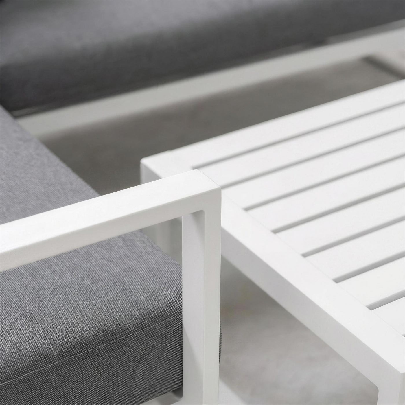 Detalle del brazo de aluminio blanco del sofa Adel-7 junto al tablero de lamas de la mesa de centro