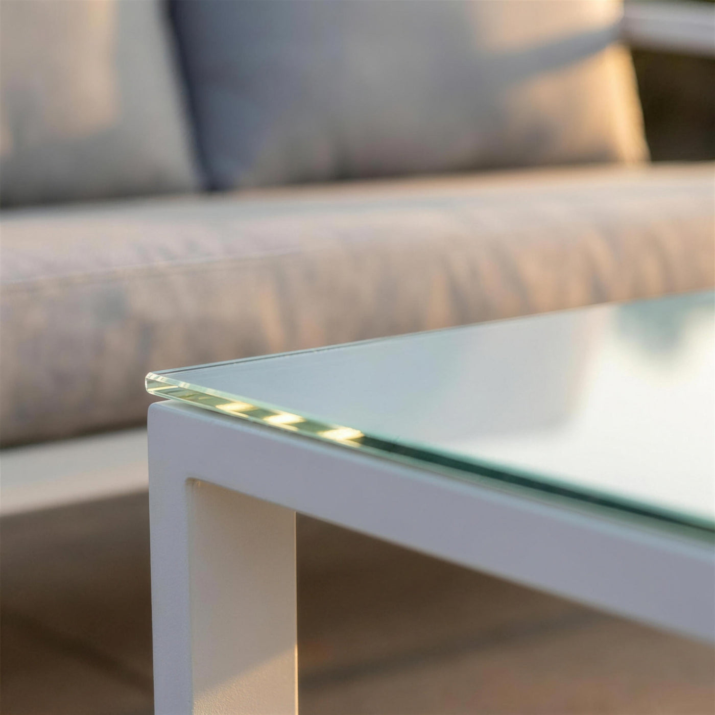Detalle del canto del tablero de cristal de la mesa de centro Acapulco sobre la estructura de aluminio blanco