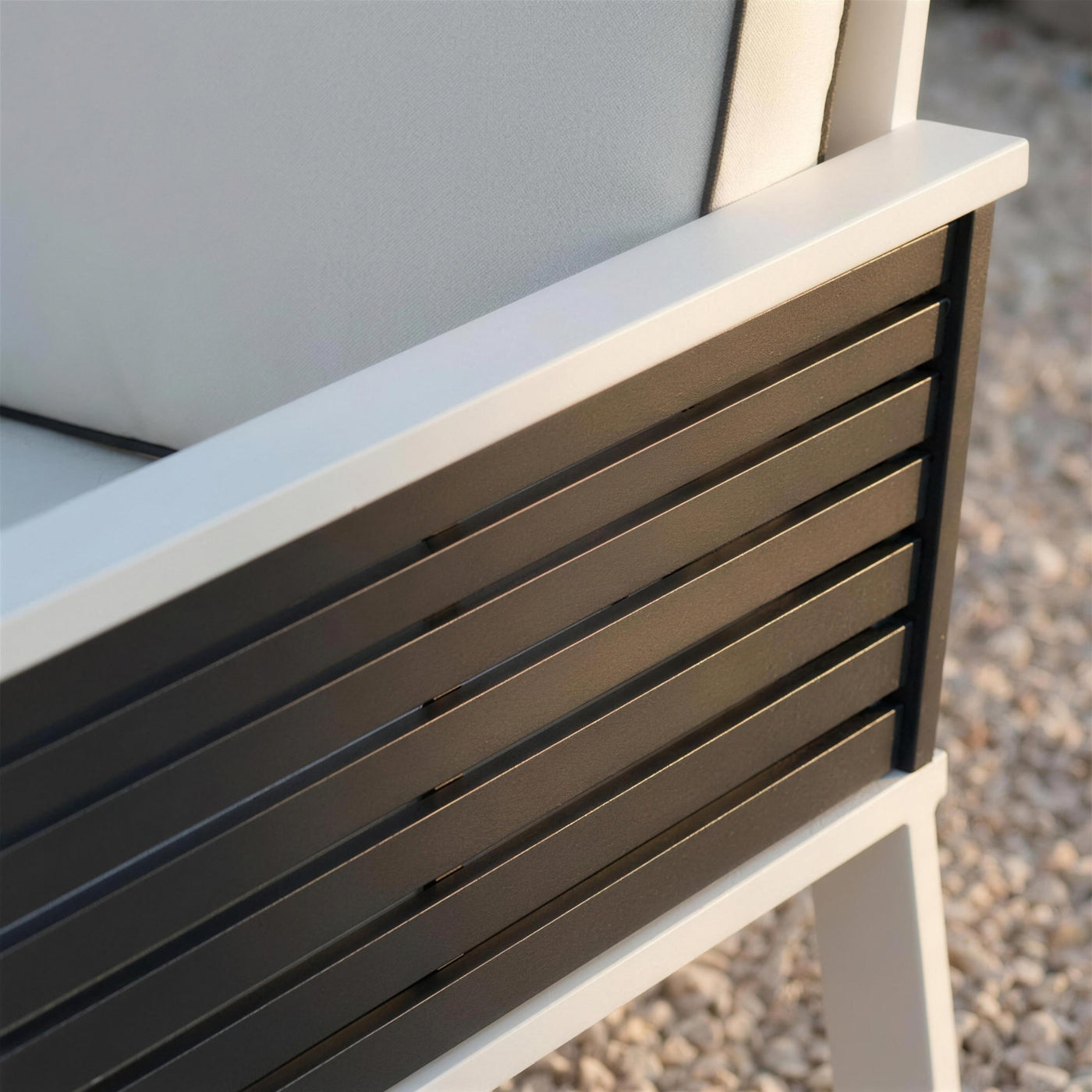 Detalle del lateral del sillón: lamas de aluminio antracita encajadas en el marco blanco junto al cojín crudo