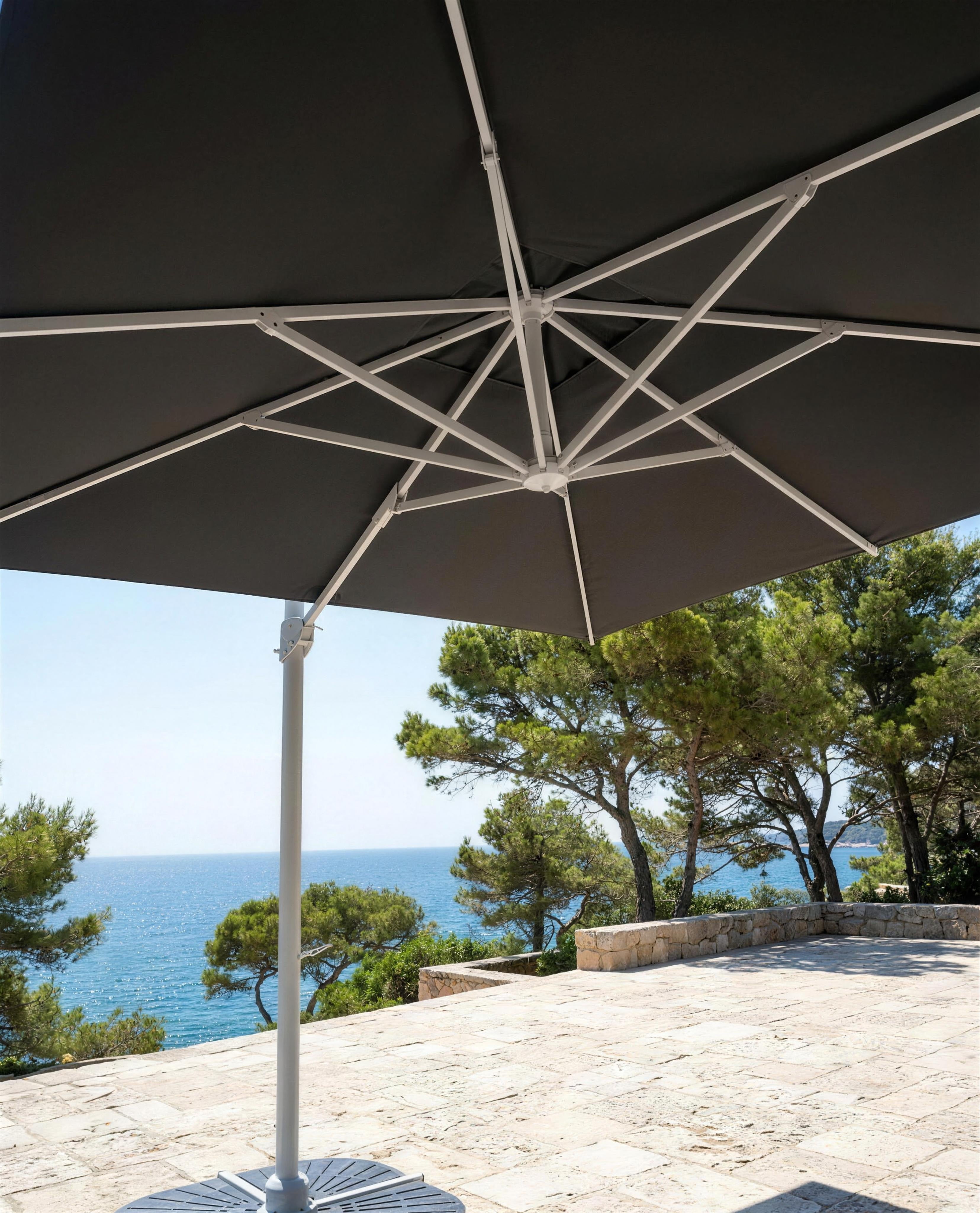 Vista bajo un parasol de aluminio en una terraza de piedra frente al mar