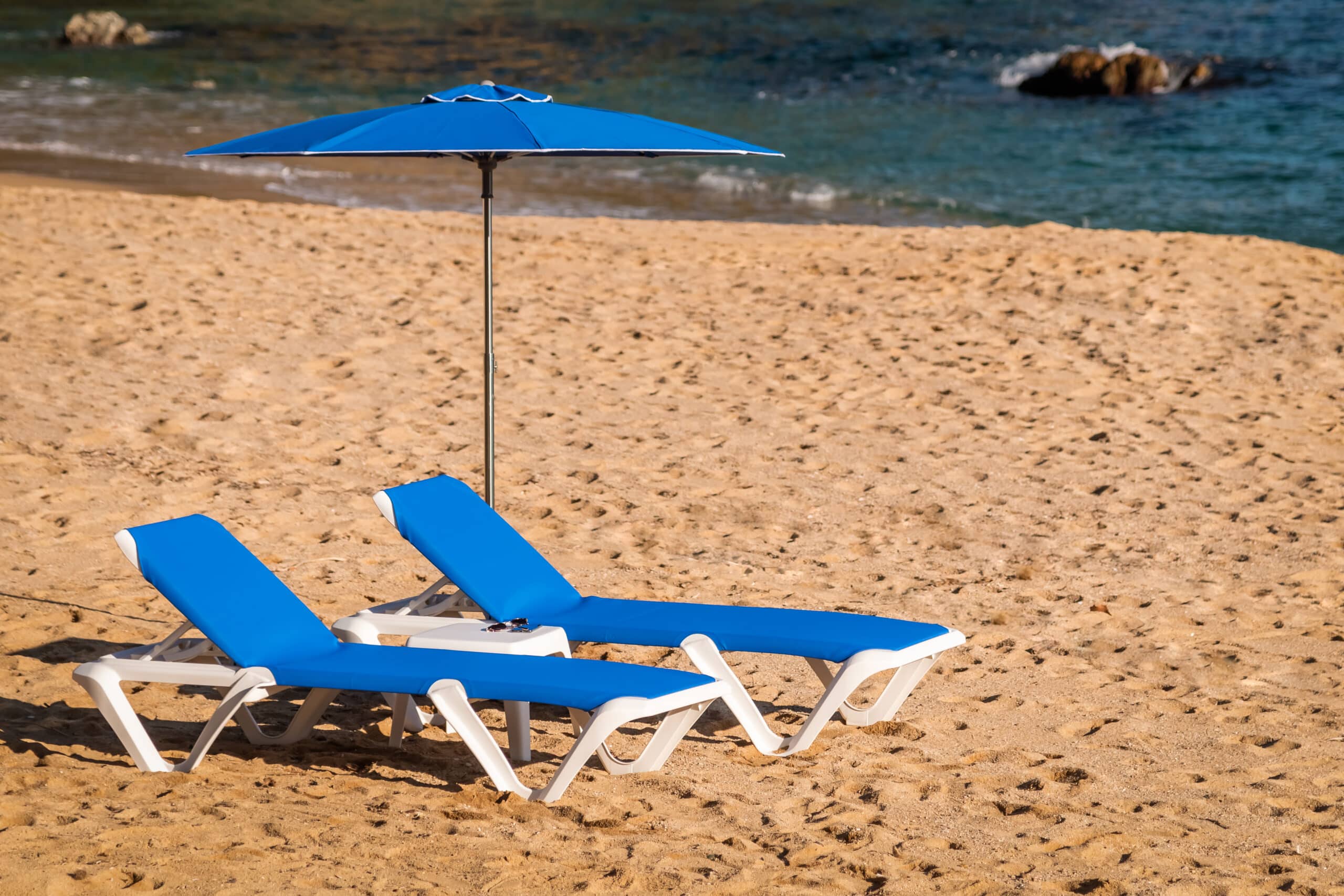 Tumbonas y parasol de exterior junto al mar para protegerse del sol