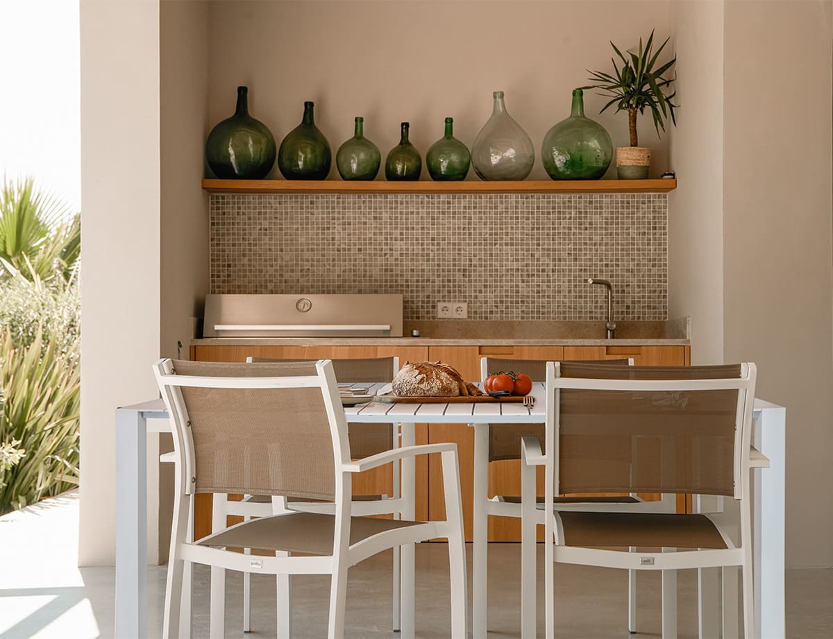 Mesa de exterior de aluminio con sillas en un porche mediterráneo