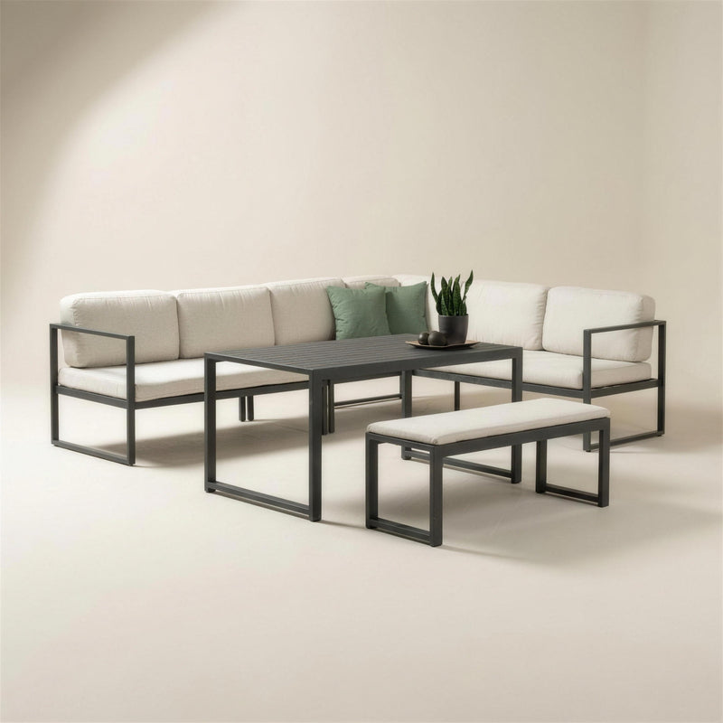 Set rinconera de exterior Adel-30 con estructura de aluminio antracita, cojines blanco crudo, mesa de lamas y banco a juego, sobre fondo neutro