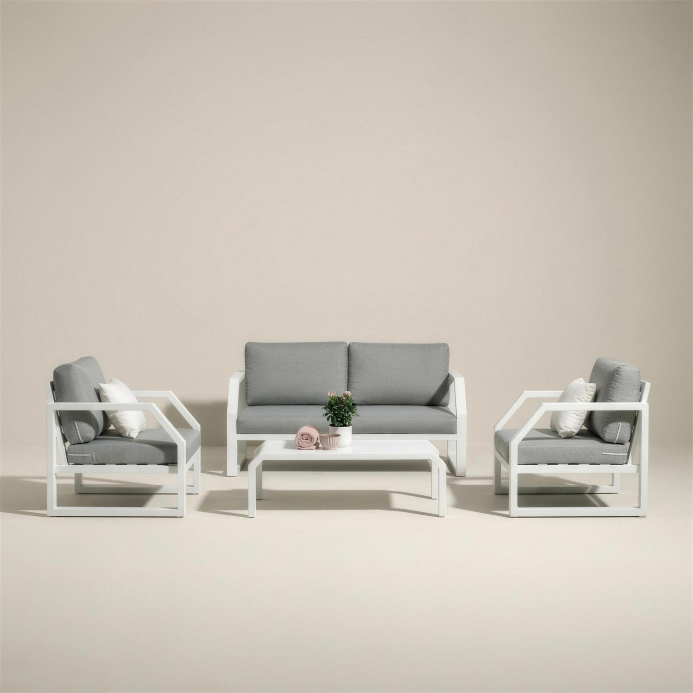 Conjunto de jardin Bellagio de 2 plazas en aluminio blanco: sofa, dos sillones y mesa de centro, con cojines gris claro, sobre fondo neutro