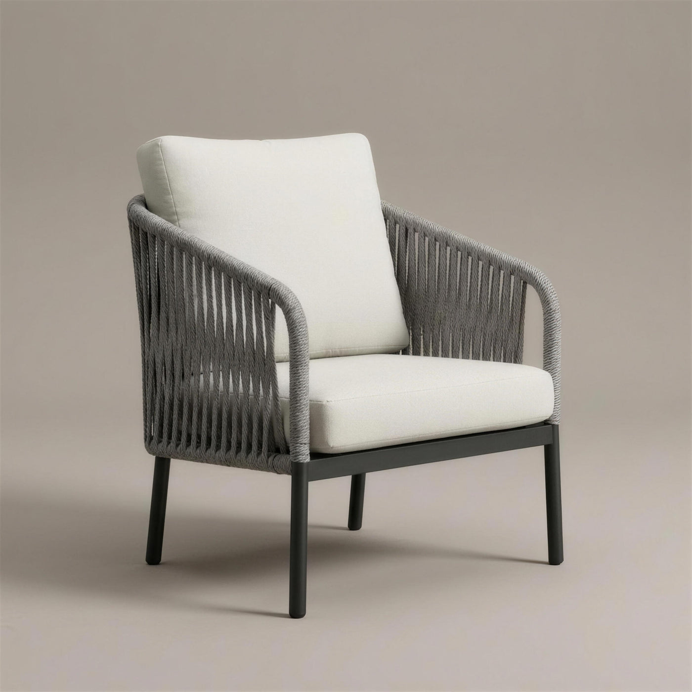 Sillon de exterior Yina con respaldo y brazos de cuerda trenzada gris sobre aluminio antracita y cojines crudo, 77x72x83 cm, sobre fondo neutro