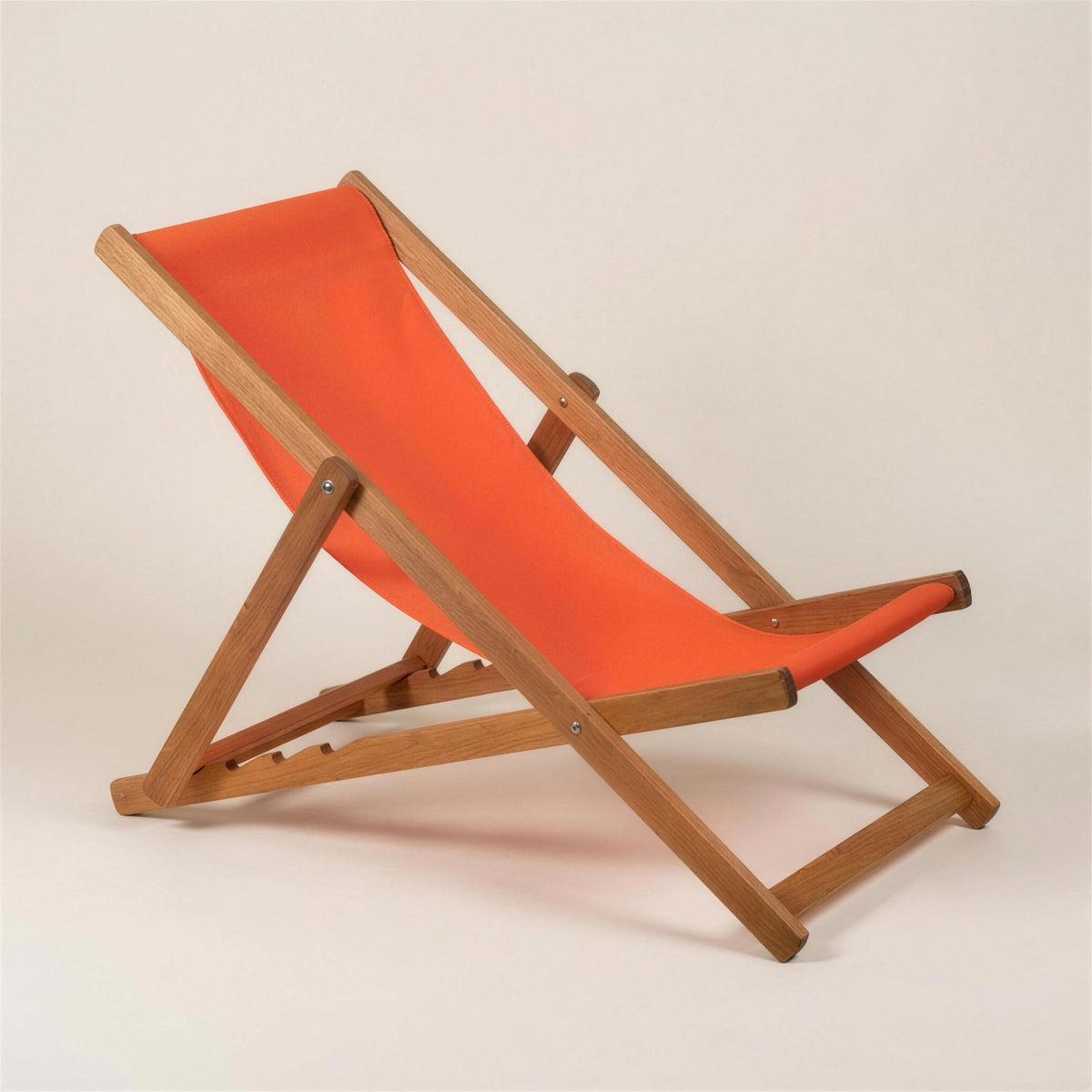 Mini tumbona plegable Bristol de madera de teca con lona naranja, sobre fondo neutro