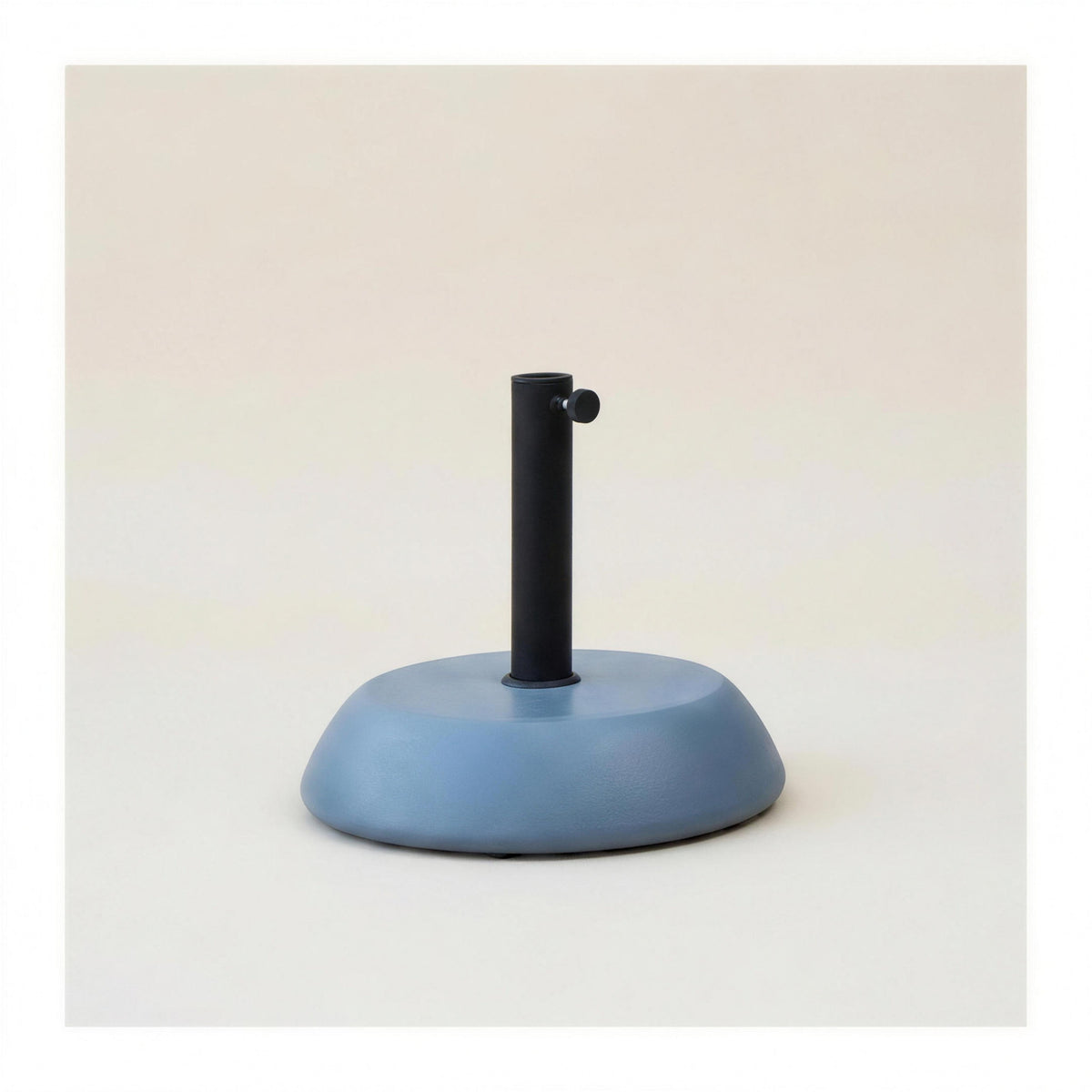 Base de parasol de hormigon de 25 kg en gris azulado, con tubo de acero negro y pomo de apriete, sobre fondo neutro