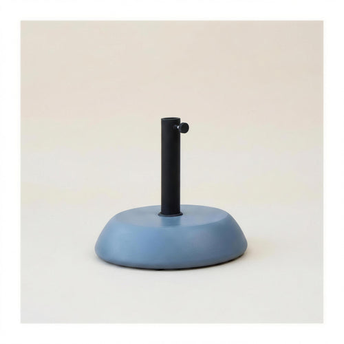 Base de parasol de hormigon de 25 kg en gris azulado, con tubo de acero negro y pomo de apriete, sobre fondo neutro