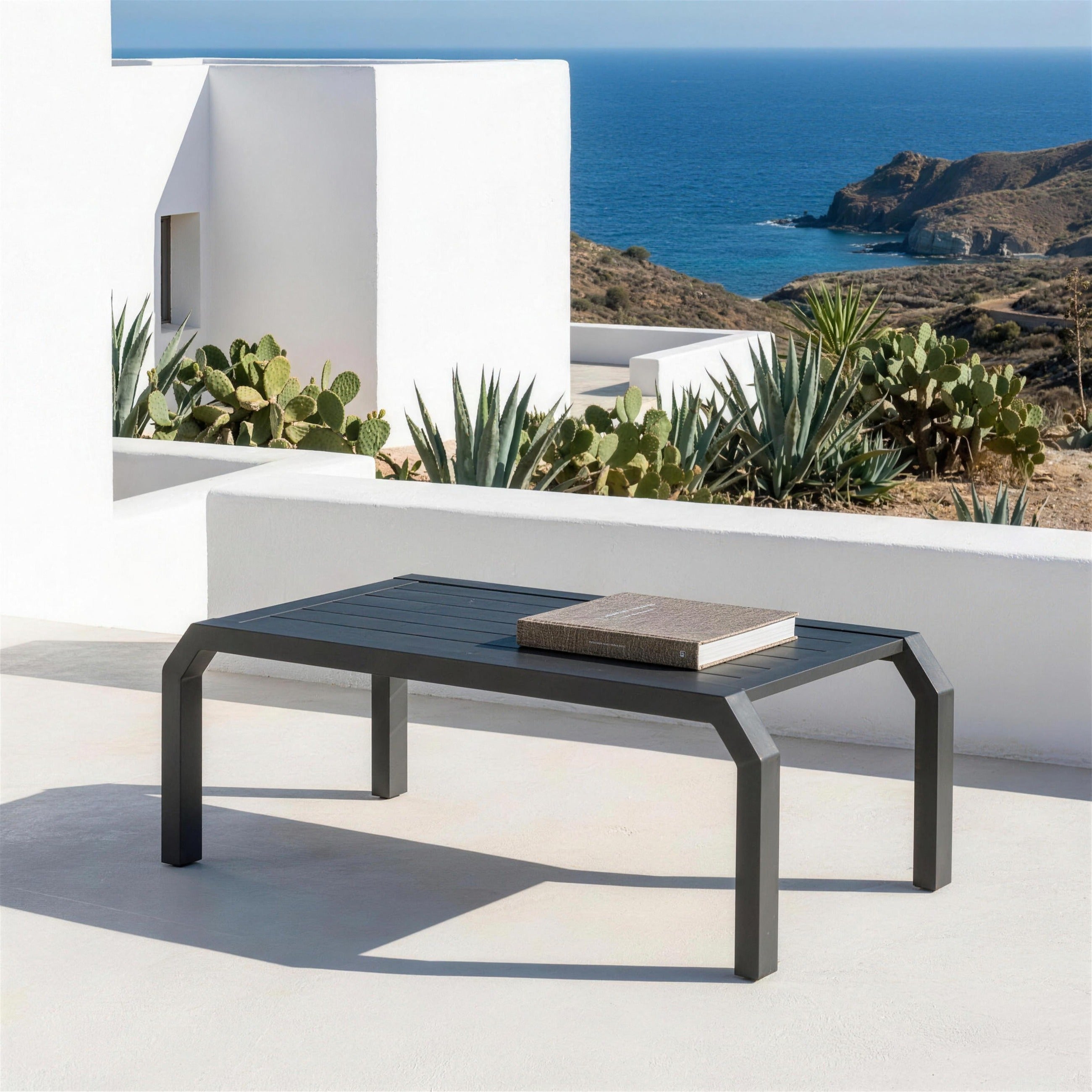 Mesa de centro Bellagio antracita sola en la terraza encalada de una casa de Cabo de Gata, entre agaves y chumberas, con el mar al fondo