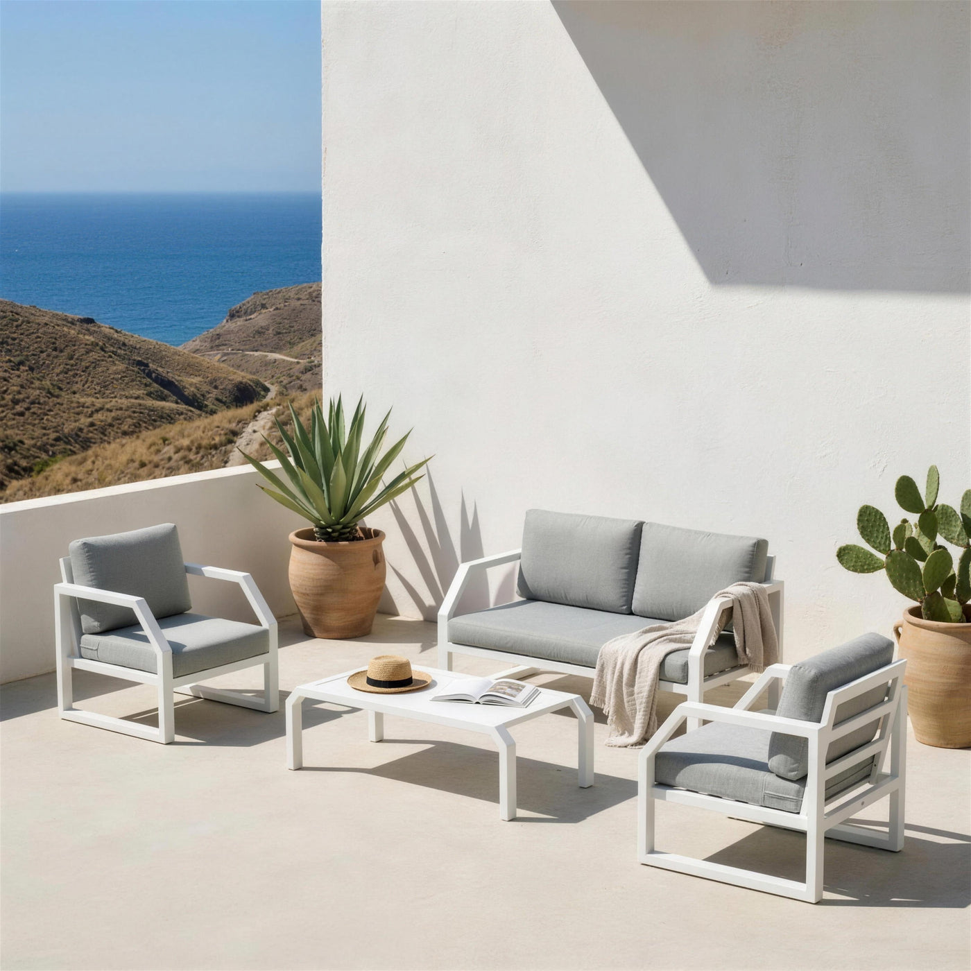 Conjunto Bellagio blanco en una terraza encalada del Cabo de Gata, entre agaves y chumberas, con el mar arido al fondo