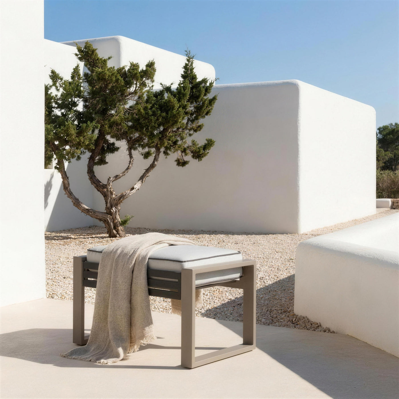 Reposapies bicolor solo en la terraza de una casa payesa de Ibiza, sobre grava clara, con muros de cal y una sabina