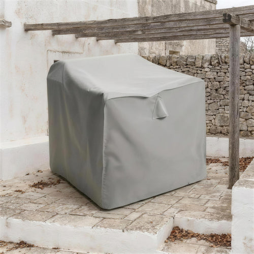 Funda protectora gris cubriendo un sofa en una terraza encalada al final de la temporada, bajo una pergola de madera desnuda. Se vende solo la funda