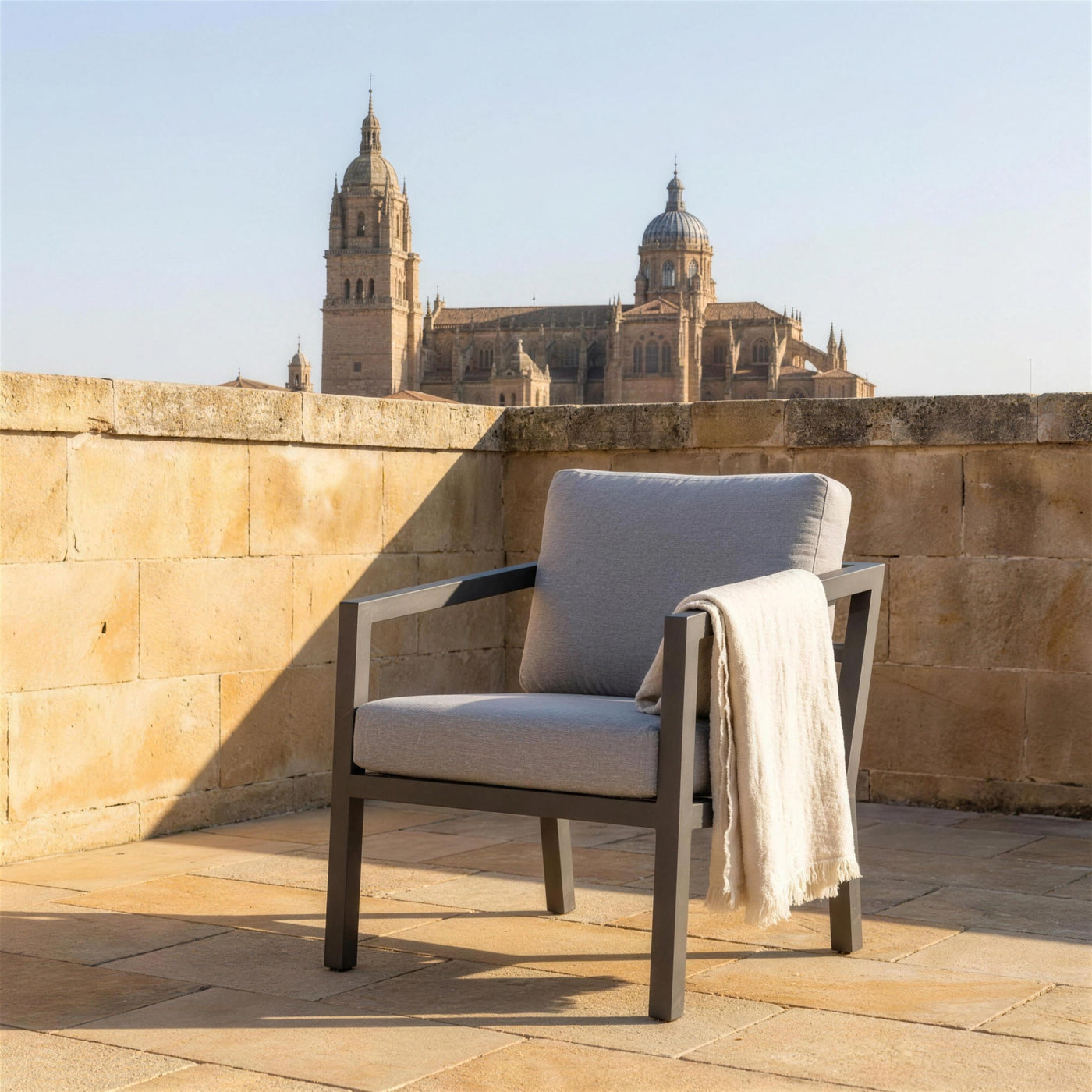 Sillon Acapulco antracita en una azotea de Salamanca, sobre suelo de piedra de Villamayor y con las torres de la catedral al fondo