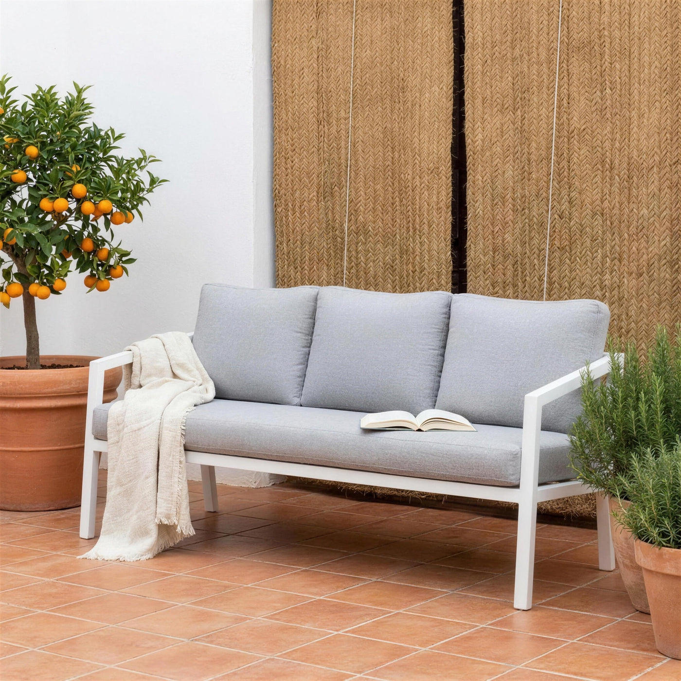 Sofa Acapulco de 3 plazas blanco en una terraza valenciana de suelo de barro, con persiana de esparto, un naranjo en tinaja y romero