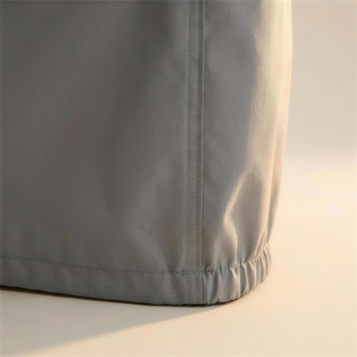 Detalle de la costura reforzada y el dobladillo elastico de la funda protectora gris para sofa de exterior