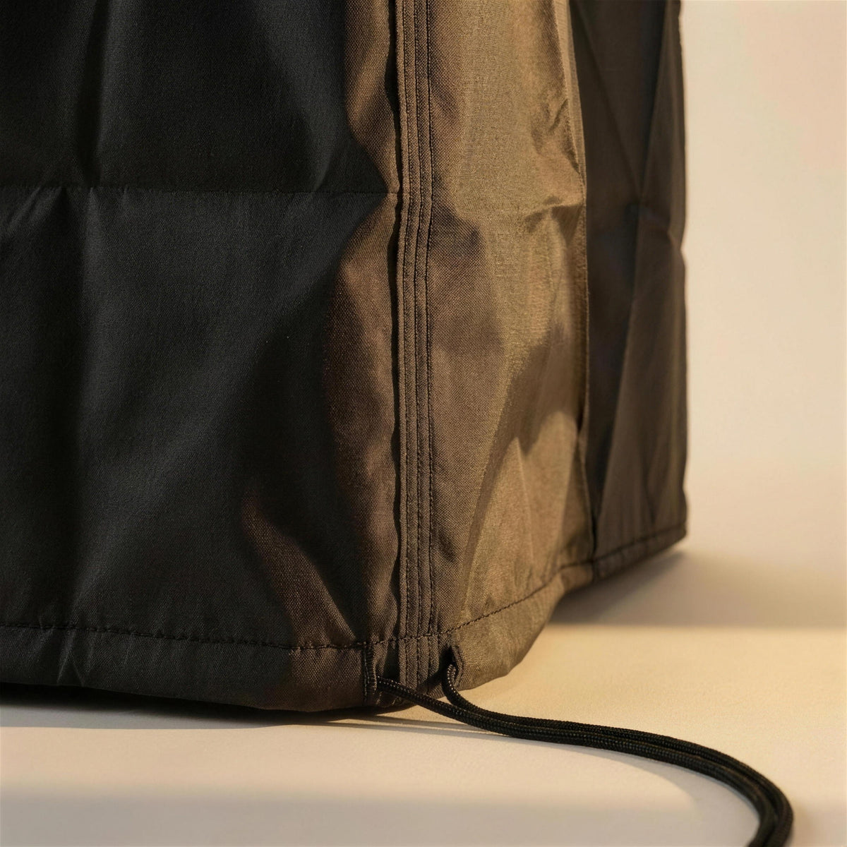 Detalle de la cremallera lateral y el cordon de ajuste de la funda protectora oscura para sillas apiladas