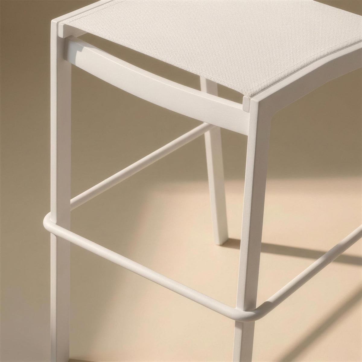 Detalle de la barra reposapies y de la union del tejido con la estructura de aluminio blanco del taburete Etna
