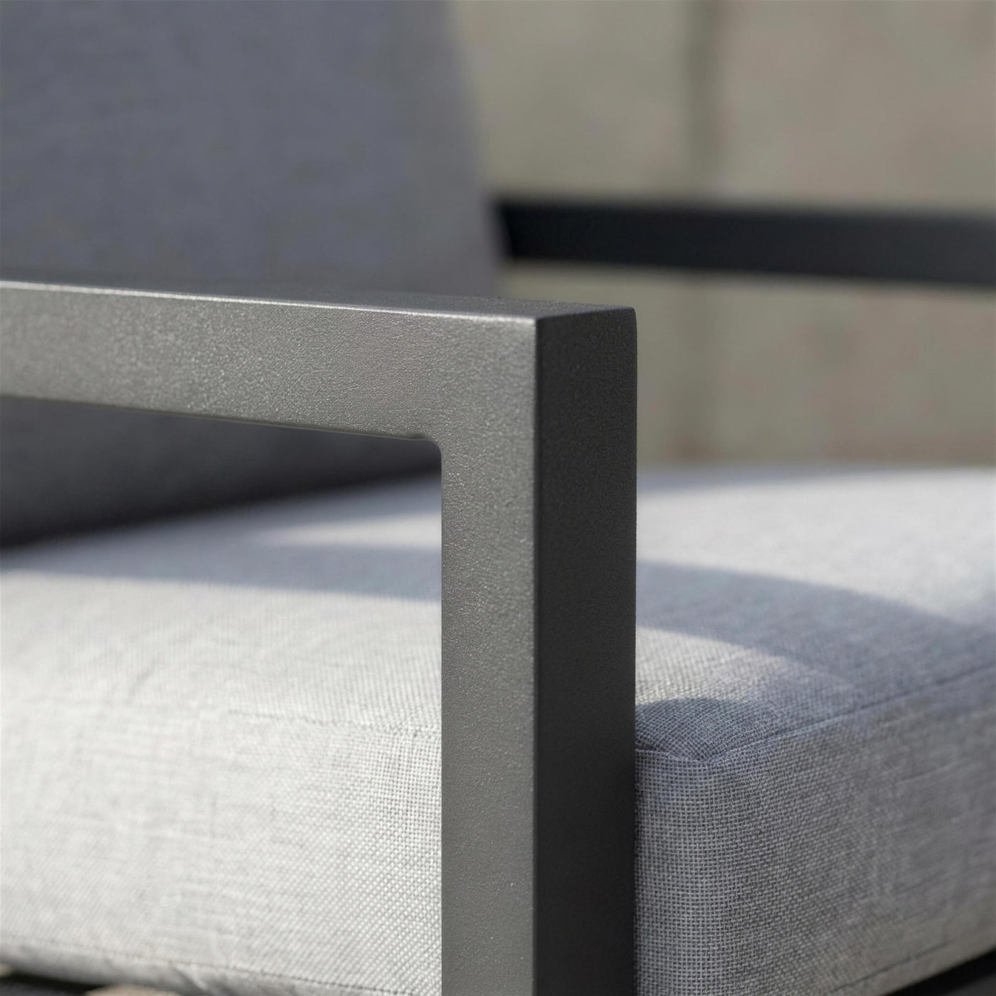Detalle del brazo de aluminio antracita del sillon Dounvil junto al cojin gris claro