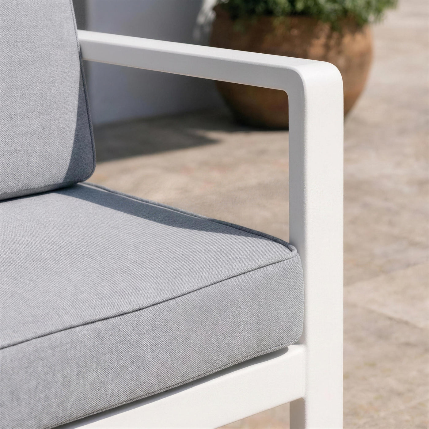 Detalle del brazo de aluminio blanco del sofa Odin y del vivo cosido del cojin gris claro
