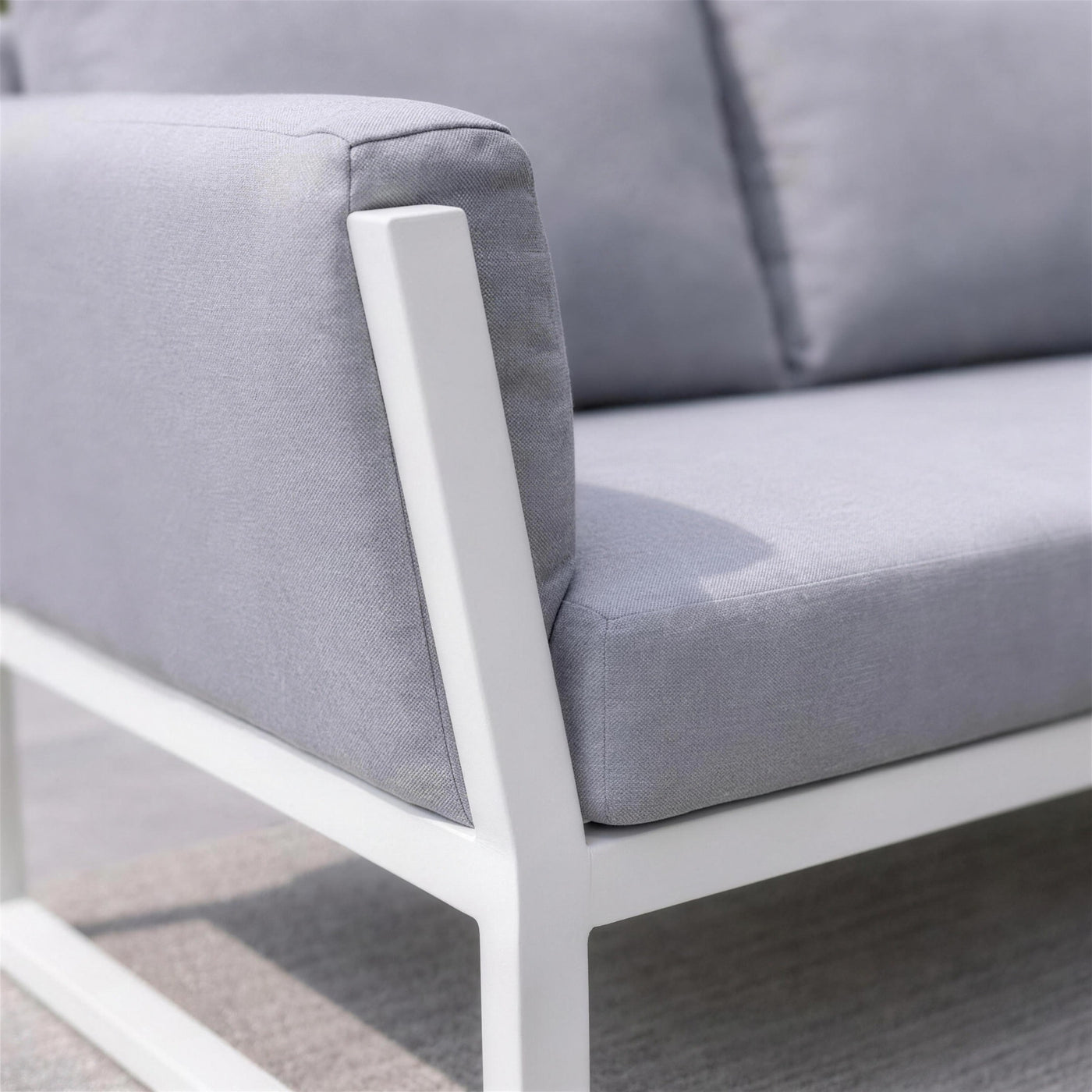 Detalle del brazo de marco abierto de aluminio blanco del sofa Cupra en su union con la base de patin