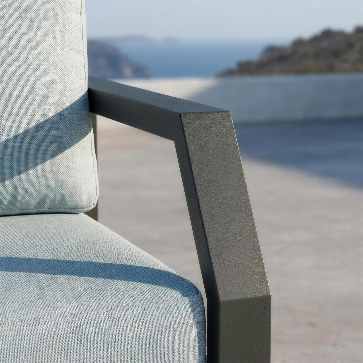 Detalle del brazo de aluminio antracita del sofa Bellagio junto al canto del cojin azul claro