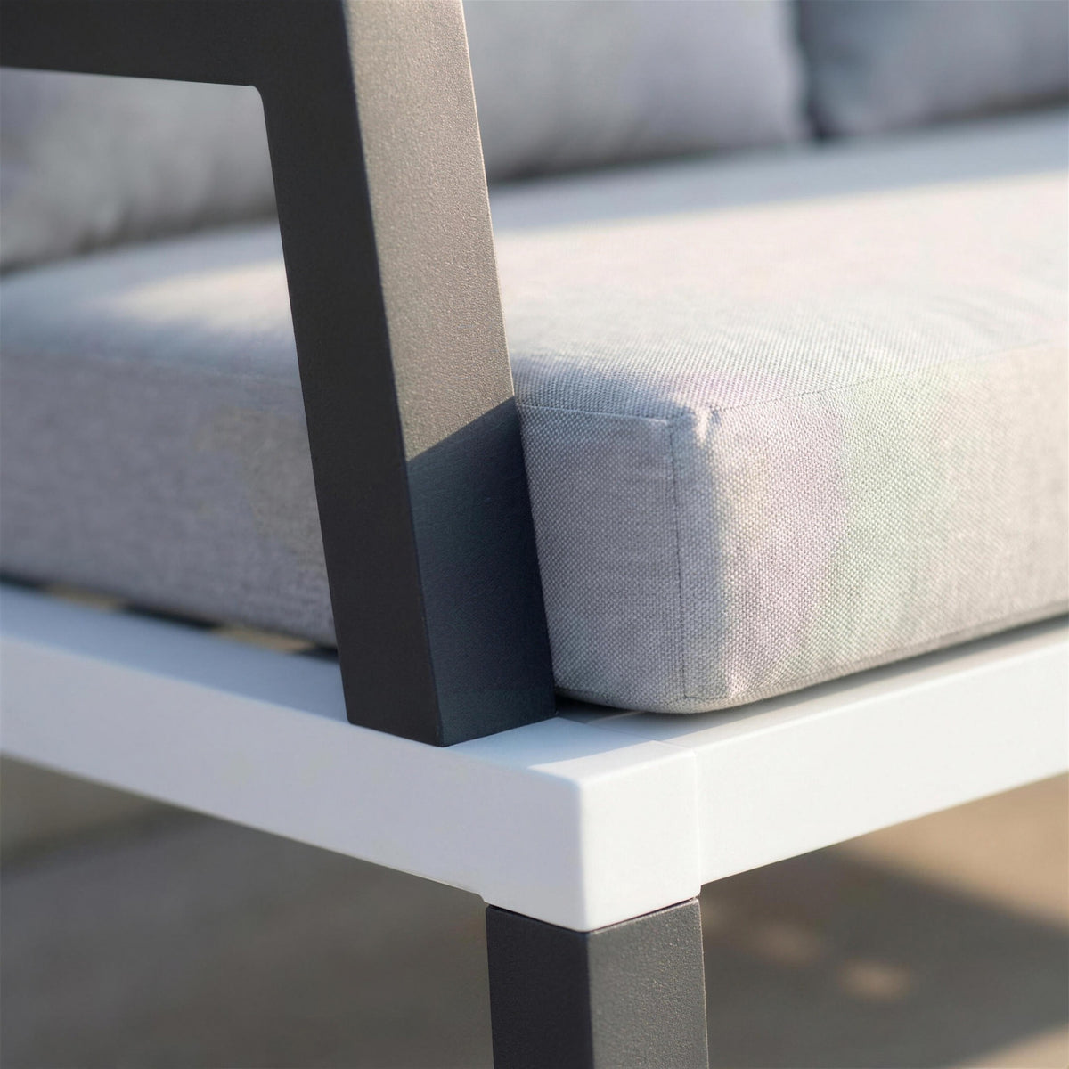 Detalle del brazo de aluminio antracita del sofa Leisa en su encuentro con el travesano blanco del chasis