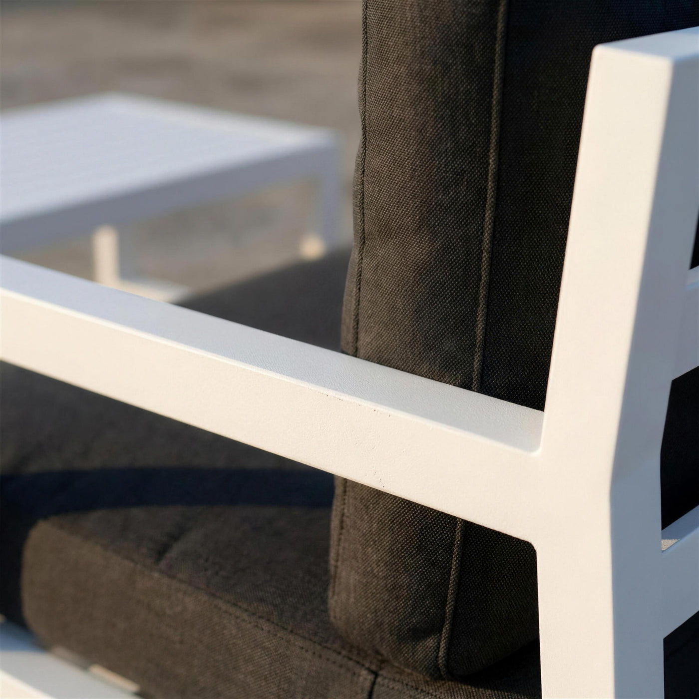Detalle del brazo de aluminio blanco del sofa Leisa junto a la costura del cojin gris marengo