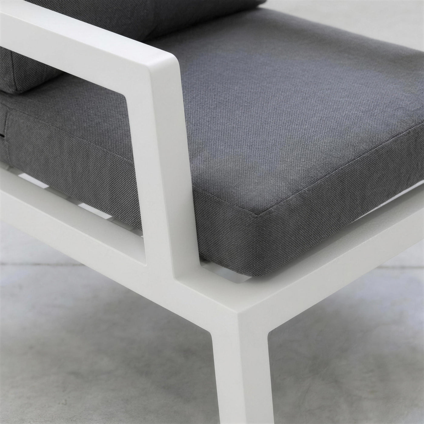 Detalle del brazo de aluminio blanco del sillon Leisa, con las lamas del asiento y la trama del cojin gris marengo