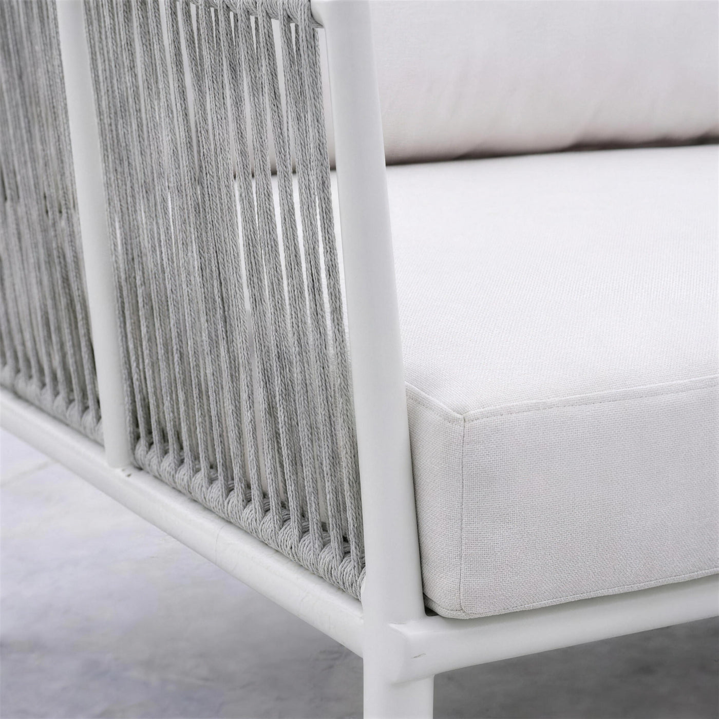 Detalle de la cuerda gris enrollada en el tubo de aluminio blanco del lateral del sofá