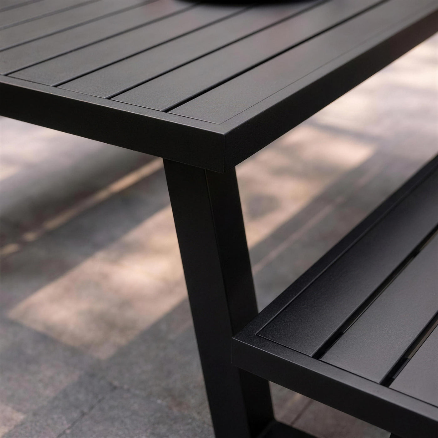 Detalle de las lamas negras mate del tablero Yulien y su encuentro con la pata trapezoidal de aluminio