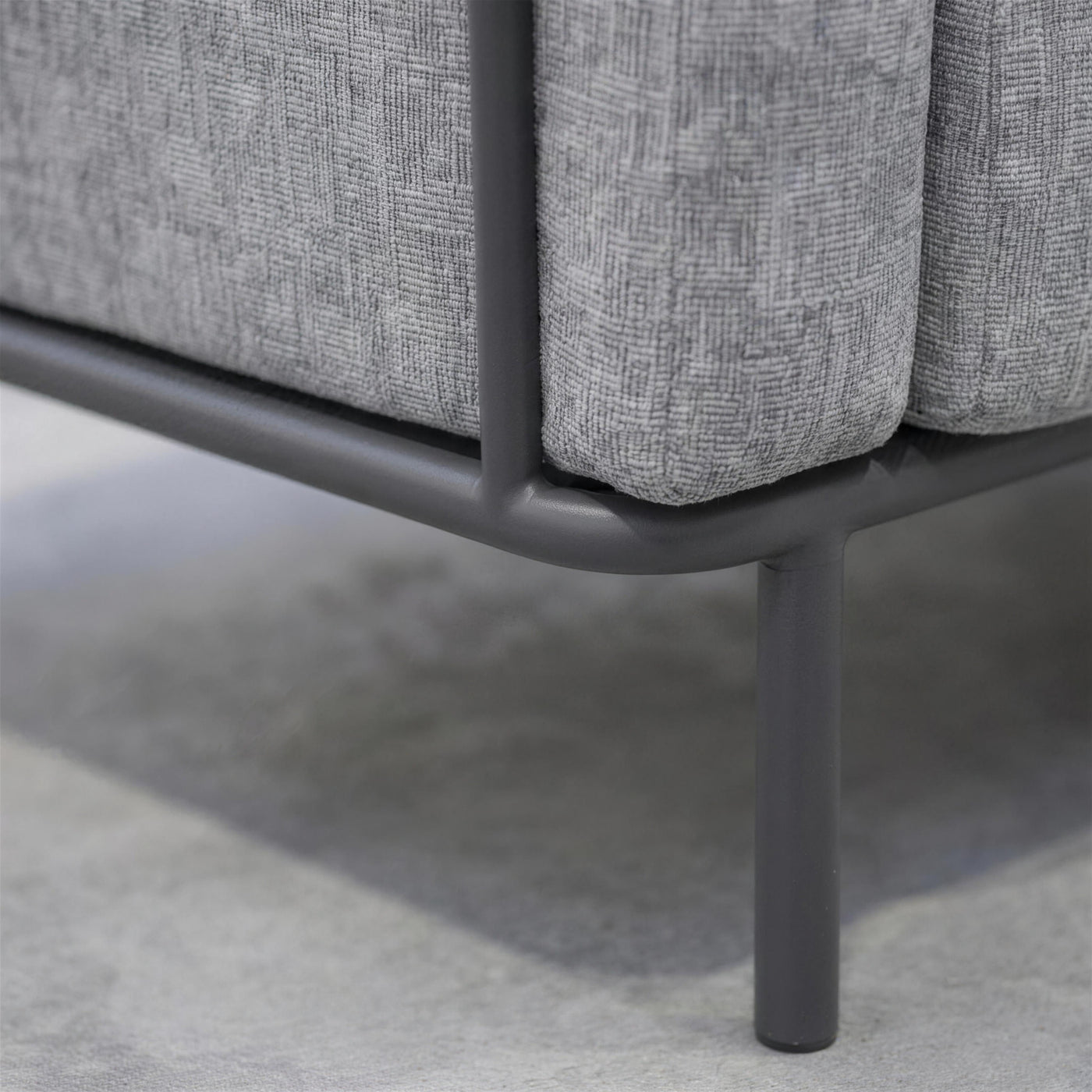 Detalle del perfil de aluminio antracita del sofa y su union con la pata cilindrica, con el tejido gris jaspeado encima