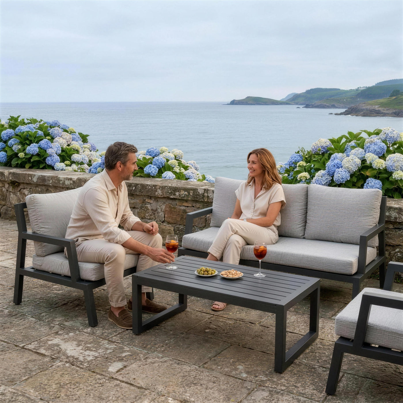 Conjunto LEISA en una terraza de la costa cantábrica con una pareja conversando frente al mar