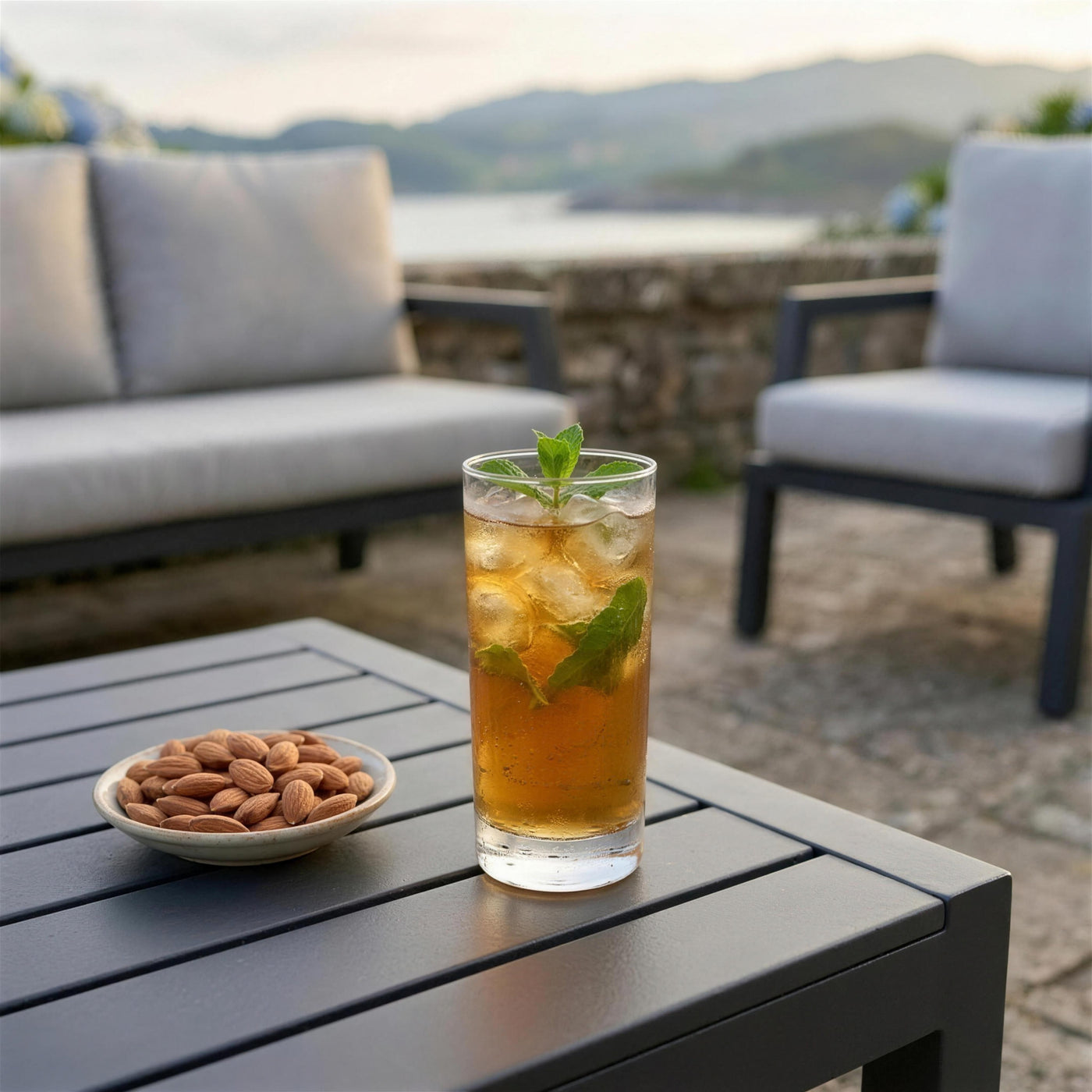 Té helado con menta y almendras sobre la mesa del conjunto LEISA en una terraza costera
