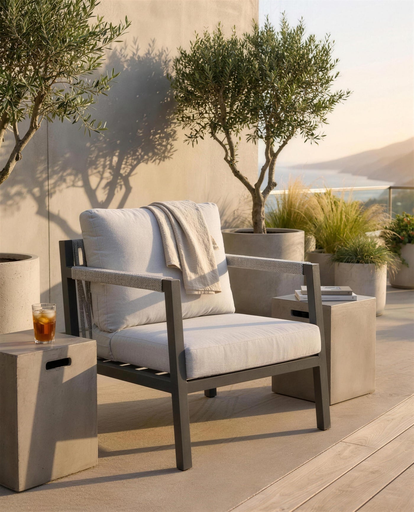 Sillón de exterior antracita en terraza contemporánea al atardecer, ambiente cálido con vistas